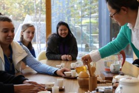 Person pouring tea from a tea pitcher with other tea items surrounding them. Person pouring tea from a tea pitcher with other tea items surrounding them.